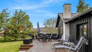 Eine Terrasse mit Gartenmöbeln, einem Tisch und Stühlen.