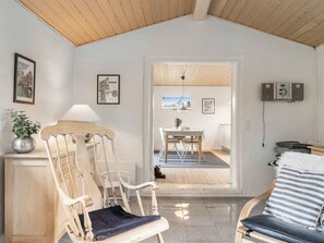 Ein Zimmer mit Holzboden, einem Essbereich mit Tisch und Stühlen, einer Couch, einer Lampe und gerahmten Bildern an den Wänden.