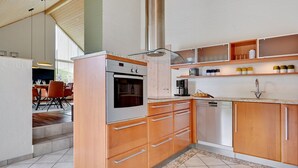 Une cuisine moderne avec des meubles en bois, un four encastré et une machine à café.
