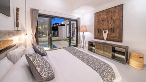 Une chambre moderne avec un grand lit, une tête de lit en bois, une console et une vue sur l’extérieur.