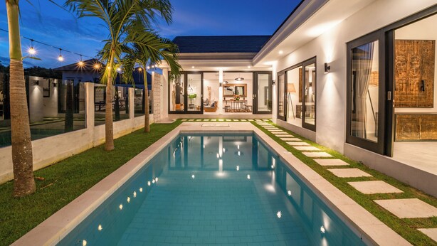 Une maison moderne dotée d’une piscine, de grandes fenêtres et d’un intérieur bien éclairé.
