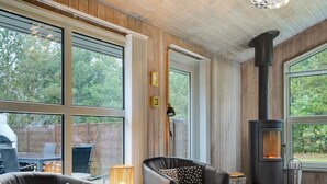 Une pièce chaleureuse avec une cheminée, de grandes fenêtres et des sièges confortables.