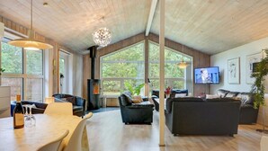 Un salon spacieux doté d’une grande cheminée, de sièges confortables et de larges fenêtres offrant une vue sur l’extérieur.