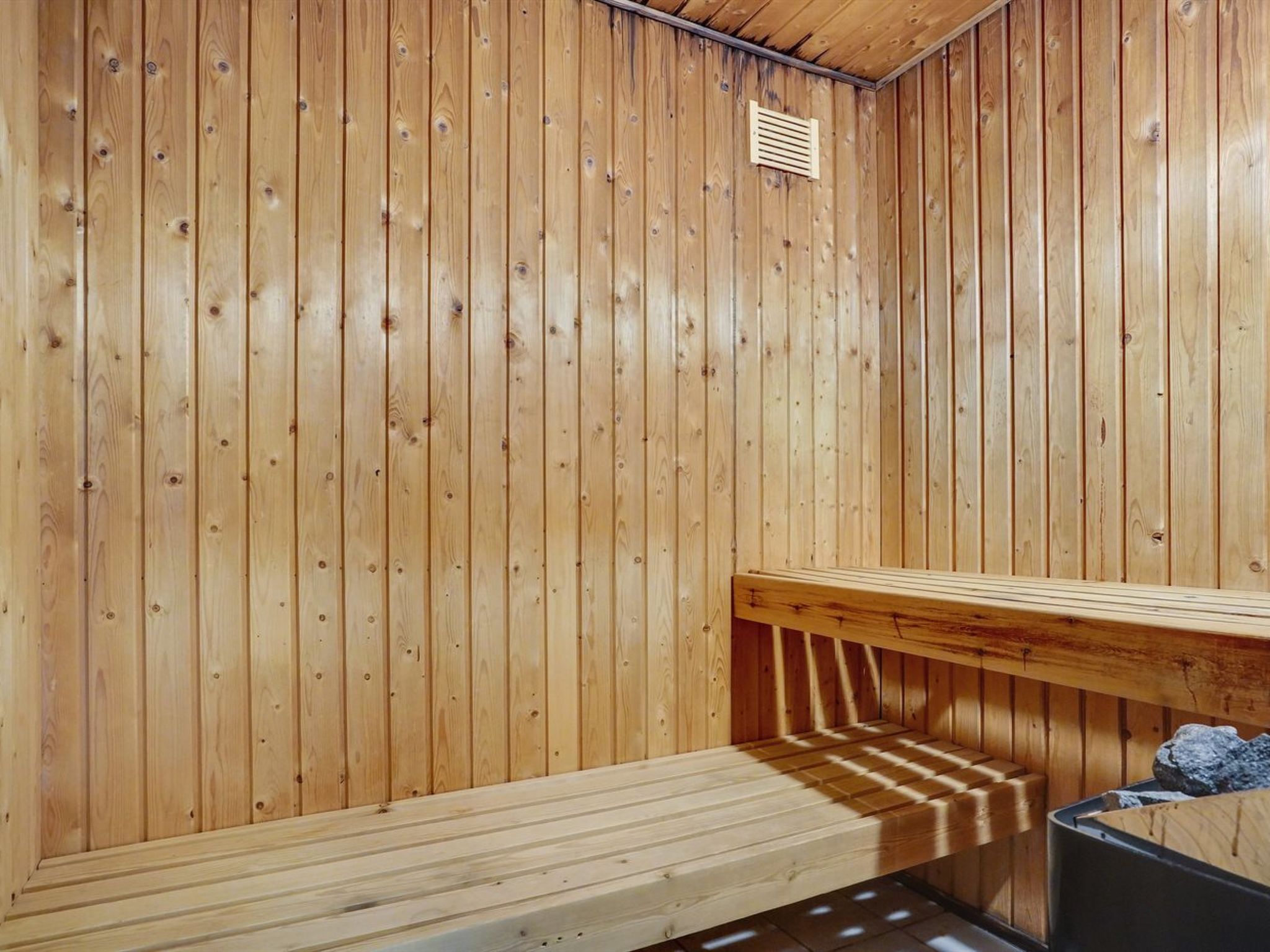 A sauna room with wooden walls and a bench.