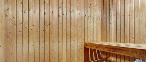 A sauna room with wooden walls and a bench.