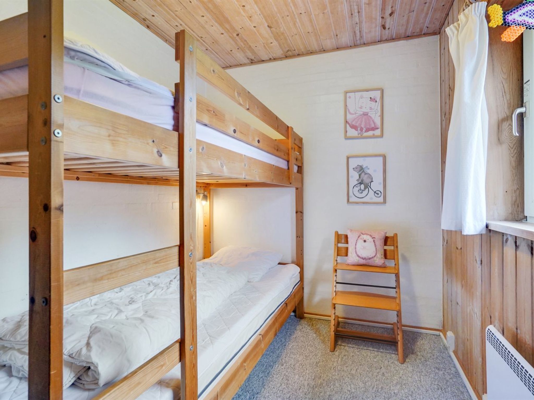 Une chambre avec un lit superposé, un plafond en bois et une petite chaise.