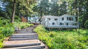 Ein Haus mit einer Holztreppe, die zu einer Terrasse führt, umgeben von dichtem Grün.