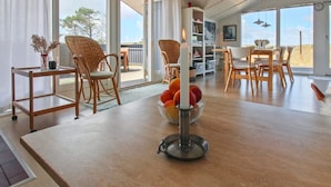 A spacious dining area with a wooden table and chairs, a fruit bowl, and a white candle.