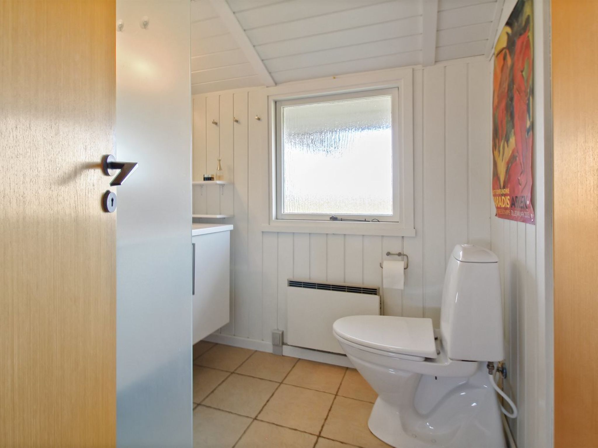 A small, clean bathroom with a toilet, a window, and a radiator.