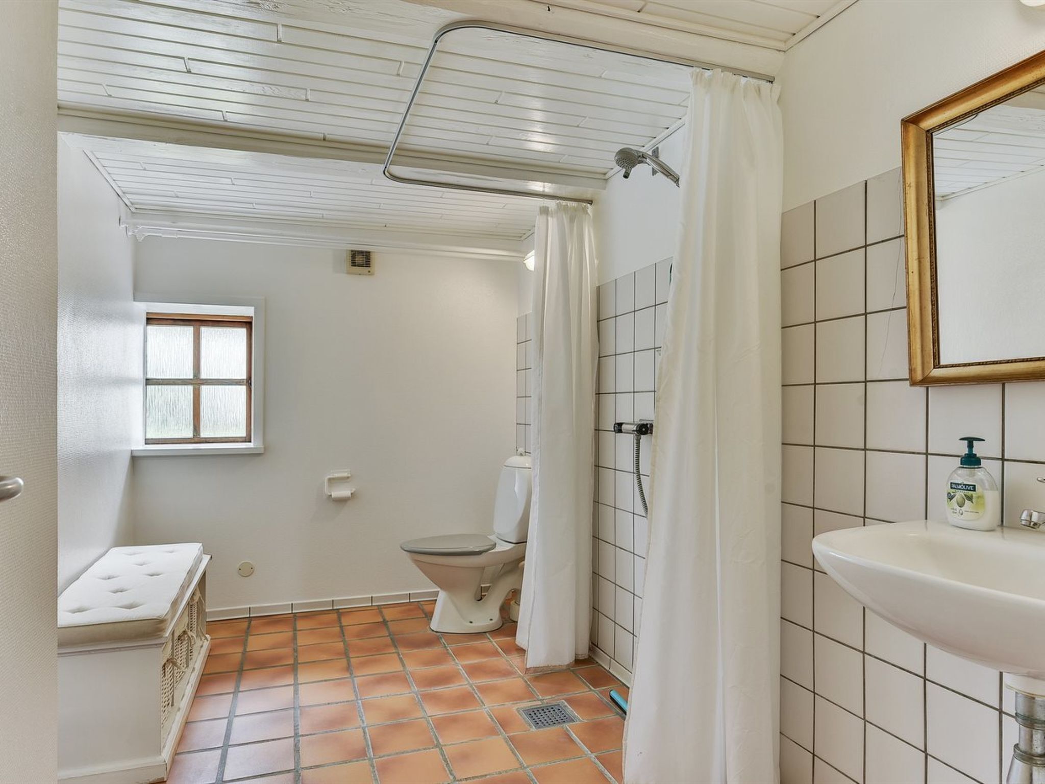 A bathroom with a toilet, shower, and sink.