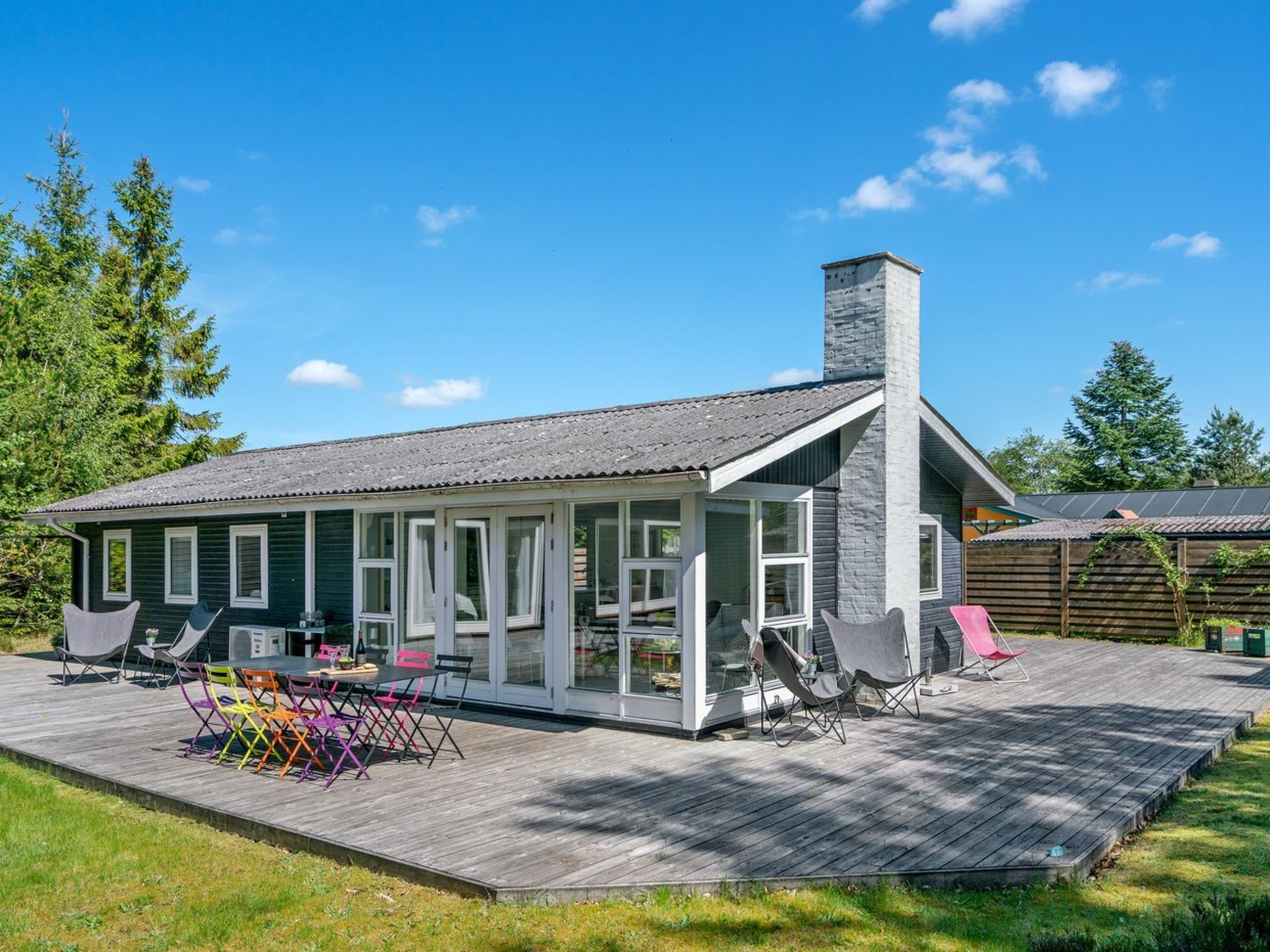Une maison à deux étages dotée d’un patio couvert, d’une cheminée et d’une terrasse aménagée avec du mobilier d’extérieur.