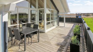 Una casa moderna con un'ampia porta in vetro che dà su un terrazzo esterno.
