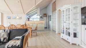 Un'ampia zona giorno con tavolo da pranzo, sedie, divano e mobile con ante in vetro.