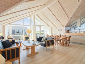 Un vaste espace de vie doté d’un haut plafond, de grandes fenêtres et de meubles en bois.