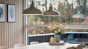 Un espace repas doté d’une grande fenêtre, de murs en bois et de deux lampes suspendues.