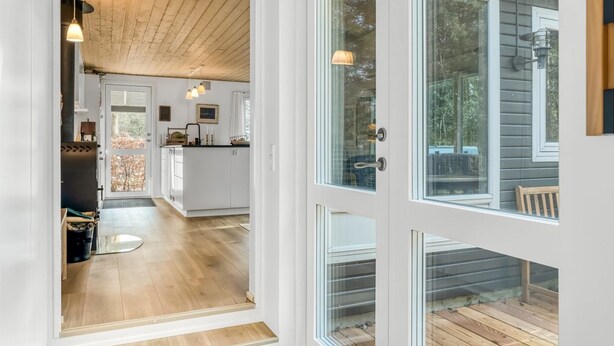 A modern kitchen with white cabinets and a wooden ceiling, a glass door leading to a deck, and a view of the outdoors. - "Milan" - 250m to the fjord by Interhome (Thyholm)
