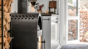 A modern kitchen with a wood-burning stove, white cabinets, and a large window. - "Milan" - 250m to the fjord by Interhome (Thyholm)