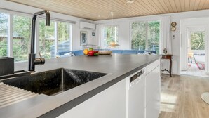 A modern kitchen with a large island, white cabinetry, and a wooden ceiling. - "Milan" - 250m to the fjord by Interhome (Thyholm)