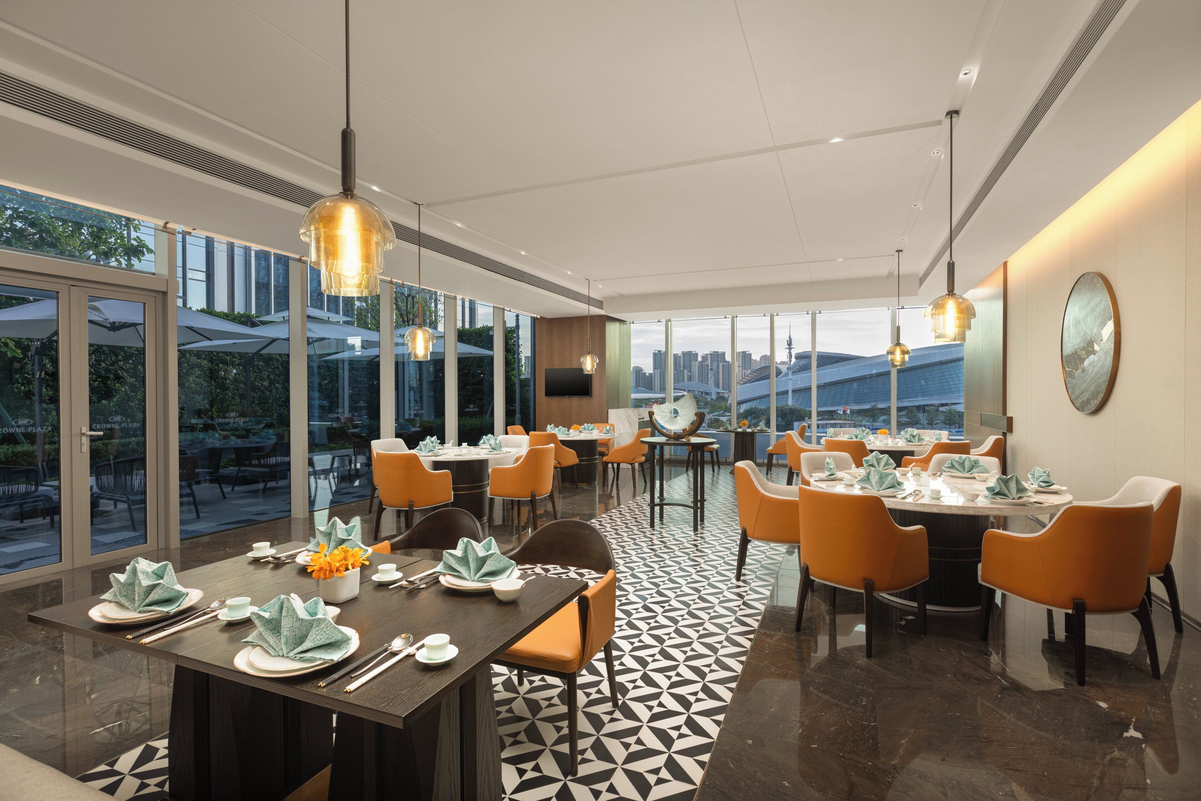 Un espace de restauration moderne, avec des tables dressées pour le service, de grandes fenêtres et une vue sur la ville.