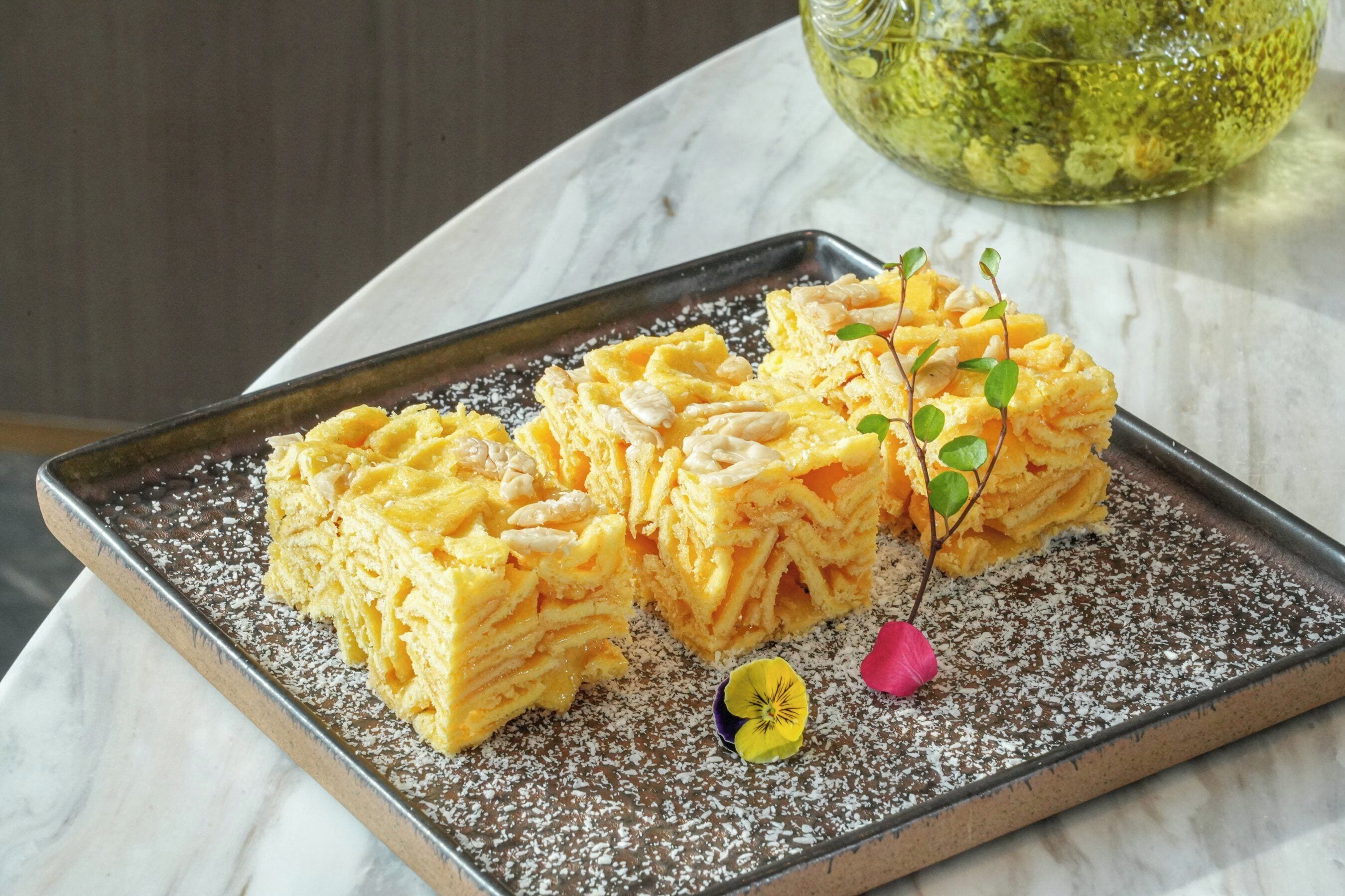A rectangular tray with layered pastry on a marble surface.
