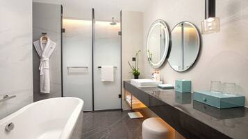 A modern bathroom with a bathtub, glass shower enclosure, dual mirrors, and a vanity with a sink and towel rack.