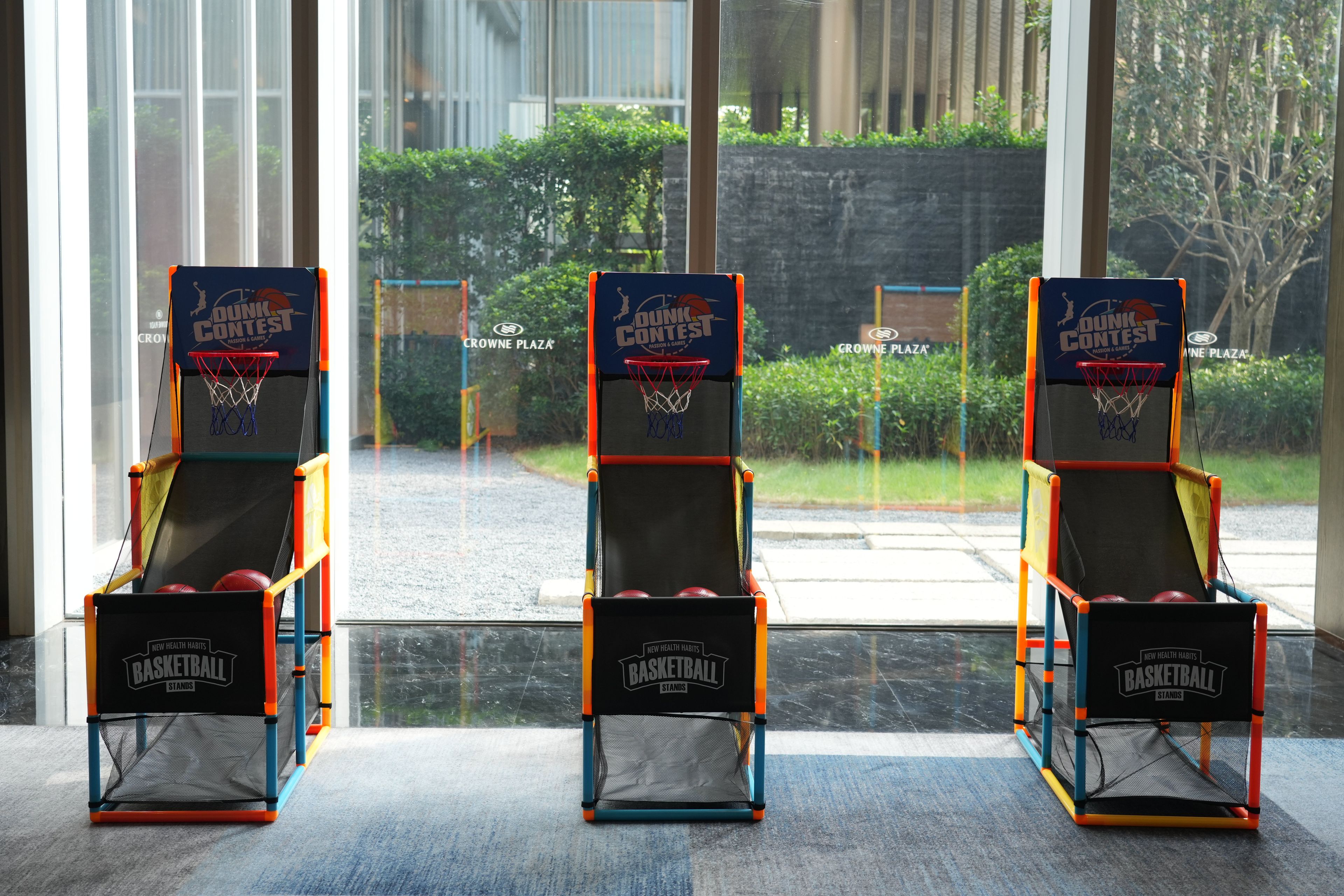 Trois paniers de basket ornés du logo « Concours de dunks », installés dans une pièce dotée de grandes fenêtres.