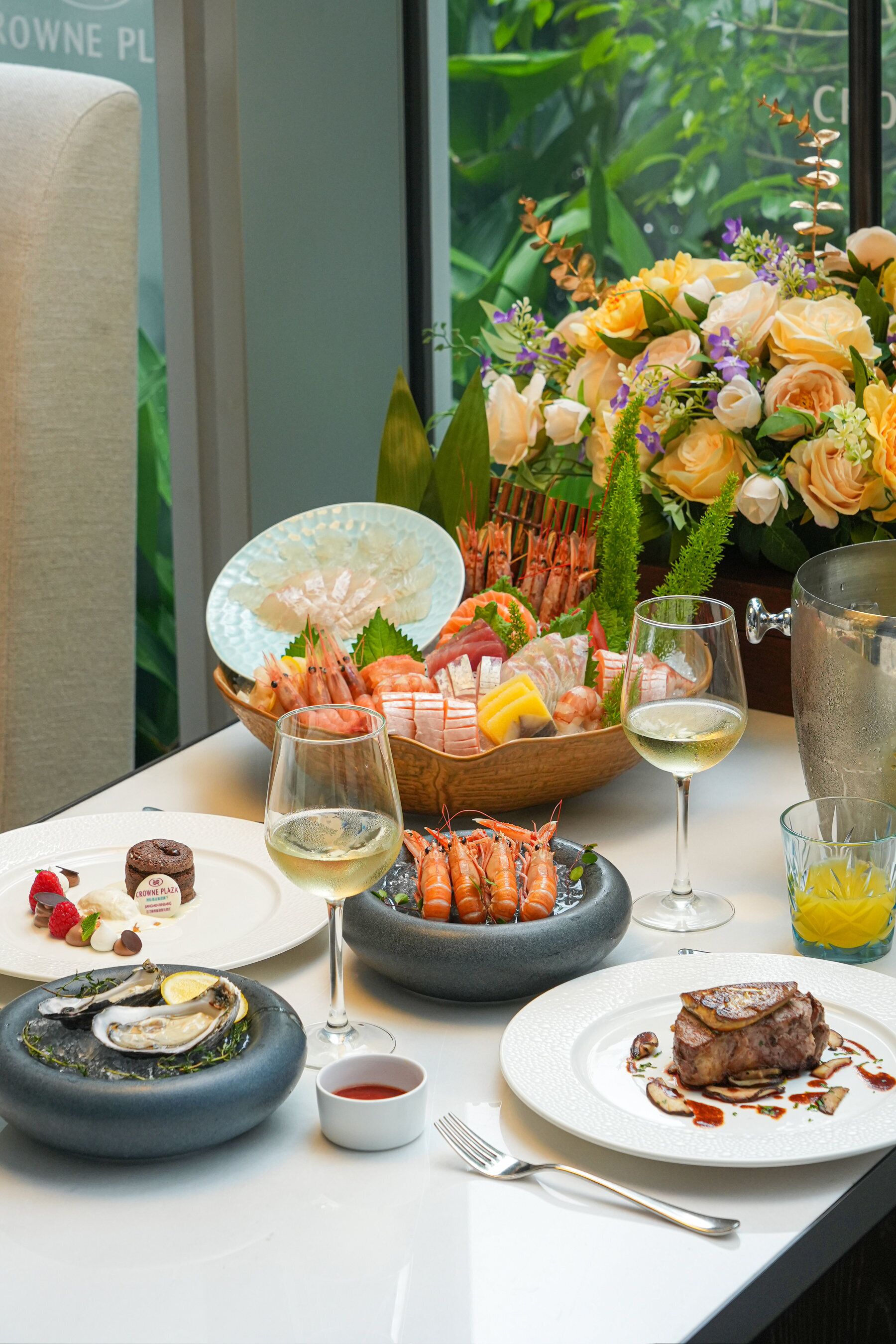 A table set with seafood, wine glasses, and a floral arrangement.