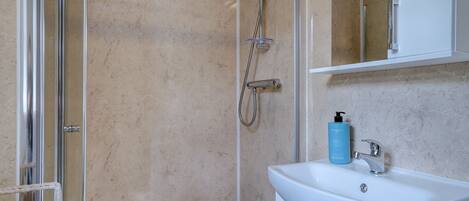 A bathroom with a glass shower enclosure, a white sink, and a mirror above it.