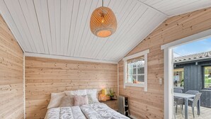 A room with wooden walls and ceiling, a bed with white bedding, a hanging light fixture, and a window overlooking an outdoor area. - "Valdemar" - 350m to the fjord by Interhome (Tarm)
