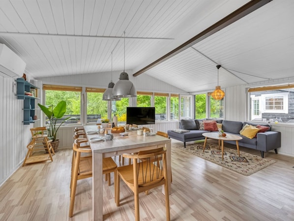A spacious living area with a dining table, chairs, a sofa, and a TV.