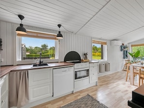 A modern kitchen with white cabinetry, a wooden countertop, and a large window.