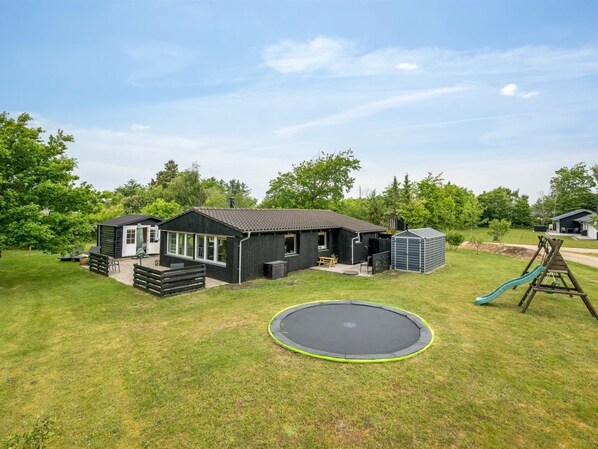 Ein Wohnhaus mit Garten, Trampolin, Spielplatz und Geräteschuppen.