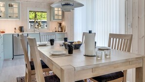 A modern kitchen with light blue cabinets, a wooden dining table, and a hanging light fixture. - "Siljan" -  from the sea by Interhome (Hals)