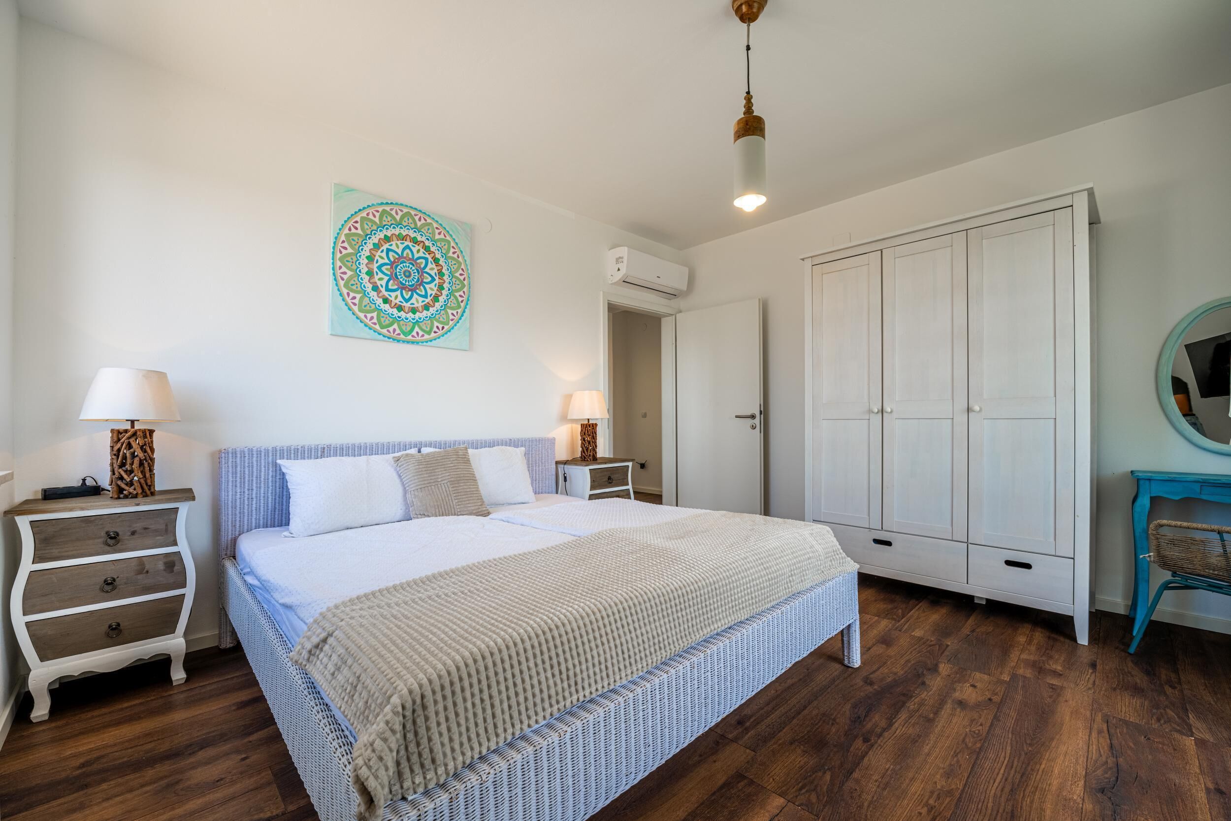 A bedroom with a bed, bedside tables, a wardrobe, and a wall decoration.