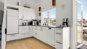 A modern kitchen with white cabinets, a built-in oven, a coffee maker, and a window with a view of the outside. - "Milo" - 5m from the sea by Interhome (Ebeltoft)