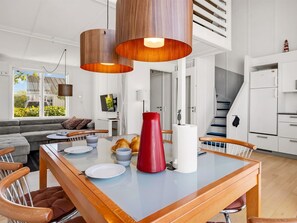 Een moderne keuken met een eettafel, stoelen en hanglampen.