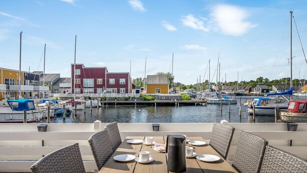 A marina with boats docked, a wooden table with chairs, and buildings in the background. - "Milo" - 5m from the sea by Interhome (Ebeltoft)