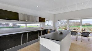 A modern kitchen with a large island, black cabinets, and a view of the outdoors.