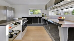 A modern kitchen with a central island, built-in appliances, and a view of the outdoors.