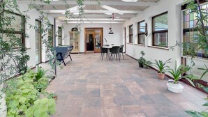 A spacious patio with a pool table, dining area, and potted plants.