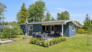 Een gelijkvloers huis met een overdekt terras, een kleine tuin en een vlag.