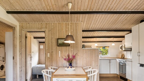 Een moderne keuken met houten kastjes, een eettafel met stoelen en een hanglamp.