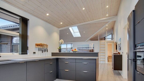 A modern kitchen with grey cabinetry, a central island, and a skylight.