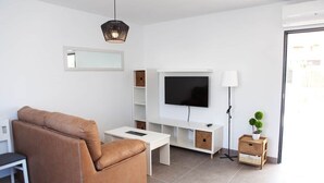 Un salon moderne avec un canapé, un téléviseur et des meubles de rangement.