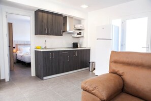 A modern kitchen with dark cabinetry, a microwave, and a refrigerator. - El chorrillo 7 (Almayate)