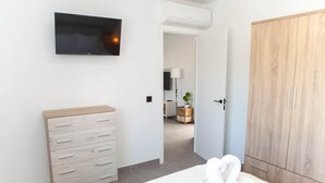 Une chambre à coucher avec un lit, une commode en bois, une armoire et un téléviseur fixé au mur.