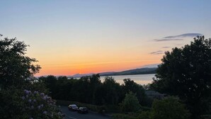 A sunset view with a road, trees, and a body of water. - Clydeview Apartments Langbank ( Gateway to Highlands ) (Langbank)