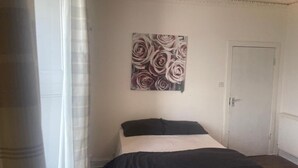 A bedroom with a bed, a door, and a painting on the wall. - Clydeview Apartments Langbank ( Gateway to Highlands ) (Langbank)