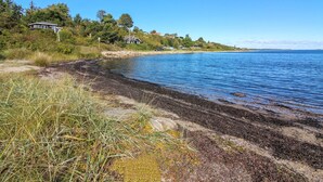 Un paisaje costero con playa, zonas verdes y casas a lo largo de la costa.