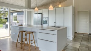 Una cocina moderna con una isla grande, electrodomésticos de acero inoxidable e iluminación colgante.